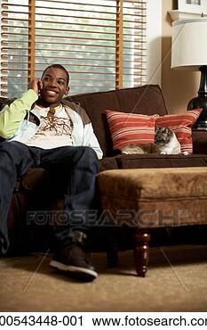 Stock Photography - cat lying beside 
teenage boy (14-16) 
talking on cell 
phone on sofa. 
fotosearch - search 
stock photos, 
pictures, images, 
and photo clipart