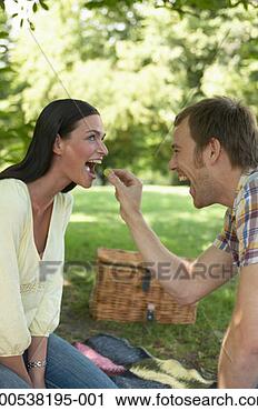 Stock Photography - couple having 
picnic in park, 
man feeding woman 
grape, smiling. 
fotosearch - search 
stock photos, 
pictures, images, 
and photo clipart
