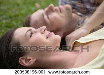 Stock Photography - couple lying on 
grass, close-up 
(focus on woman). 
fotosearch - search 
stock photos, 
pictures, images, 
and photo clipart