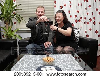 Stock Photography - couple sitting 
in living room 
raising glasses 
of red wine, smiling. 
fotosearch - search 
stock photos, 
pictures, images, 
and photo clipart