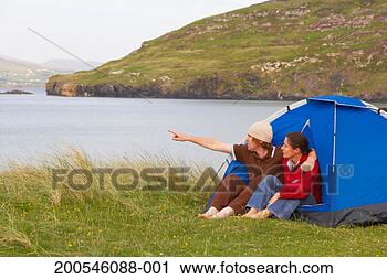 Stock Photography - ireland, donegal, 
ballymastocker 
bay couple sitting 
in tent, pointing. 
fotosearch - search 
stock photos, 
pictures, images, 
and photo clipart