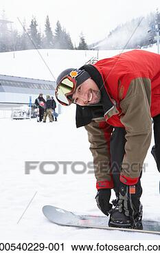Stock Photography - man adjusting 
snowboard at base 
of mountain, smiling, 
portrait. fotosearch 
- search stock 
photos, pictures, 
images, and photo 
clipart