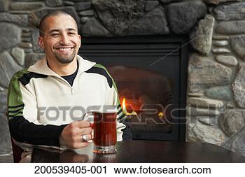 Stock Photography - man with glass 
of beer sitting 
beside fireplace, 
smiling, portrait. 
fotosearch - search 
stock photos, 
pictures, images, 
and photo clipart