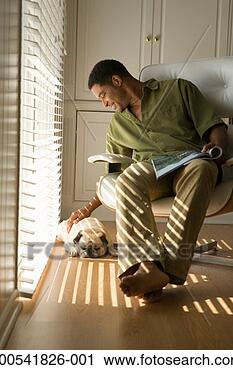 Stock Photography - mature man with 
magazine sitting 
on armchair, petting 
pug. fotosearch 
- search stock 
photos, pictures, 
images, and photo 
clipart