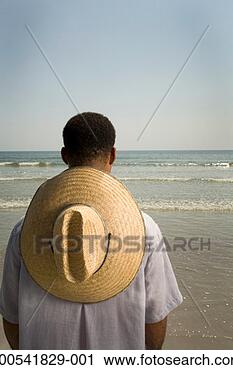 Stock Photography - mature man with 
sun hat standing 
on beach, rear 
view. fotosearch 
- search stock 
photos, pictures, 
images, and photo 
clipart