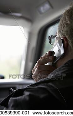 Stock Photography - mature man talking 
on cell phone 
in car, view from 
back seat. fotosearch 
- search stock 
photos, pictures, 
images, and photo 
clipart