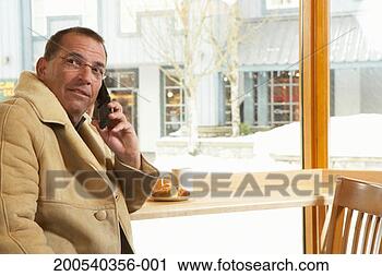 Stock Photography - mature man talking 
on cell phone 
in cafe, looking 
away. fotosearch 
- search stock 
photos, pictures, 
images, and photo 
clipart