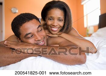 Stock Photography - mature man and 
young woman lying 
on bed, smiling. 
fotosearch - search 
stock photos, 
pictures, images, 
and photo clipart