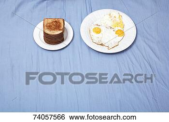 Stock Photo - plate of fried 
eggs and plate 
of toast on bed, 
elevated view. 
fotosearch - search 
stock photos, 
pictures, images, 
and photo clipart