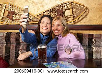 Stock Photography - two women photographing 
themselves with 
camera phone in 
pub. fotosearch 
- search stock 
photos, pictures, 
images, and photo 
clipart