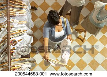Stock Photography - woman holding 
dress beside rack 
and mannequins, 
elevated view. 
fotosearch - search 
stock photos, 
pictures, images, 
and photo clipart