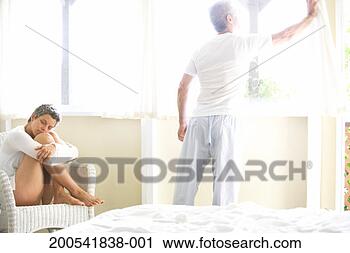 Stock Photography - woman and mature 
man in hotel room, 
man opening curtains. 
fotosearch - search 
stock photos, 
pictures, images, 
and photo clipart