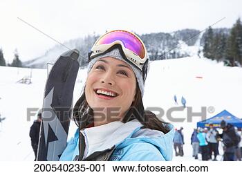 Stock Photography - woman with skis 
at base of mountain 
near ski lift, 
smiling, looking 
up. fotosearch 
- search stock 
photos, pictures, 
images, and photo 
clipart