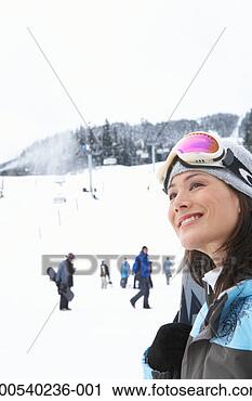 Stock Photography - woman with skis 
at base of mountain 
near ski lift, 
smiling, looking 
up. fotosearch 
- search stock 
photos, pictures, 
images, and photo 
clipart