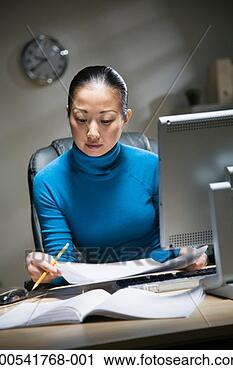 Stock Photography - young businesswoman 
working late, 
looking at documents 
at desk. fotosearch 
- search stock 
photos, pictures, 
images, and photo 
clipart