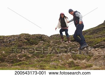 Stock Photography - young couple holding 
hands walking 
down rocky slope. 
fotosearch - search 
stock photos, 
pictures, images, 
and photo clipart