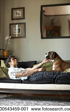 Stock Photography - young man and 
dog lying on sofa, 
man petting dog, 
side view. fotosearch 
- search stock 
photos, pictures, 
images, and photo 
clipart