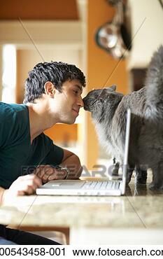 Stock Photography - young man with 
laptop and cat 
nose to nose, 
side view. fotosearch 
- search stock 
photos, pictures, 
images, and photo 
clipart