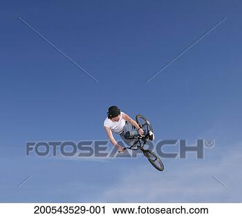 Stock Photography - young man performing 
stunt on bike 
against blue sky. 
fotosearch - search 
stock photos, 
pictures, images, 
and photo clipart