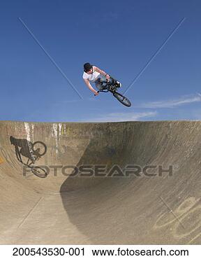 Stock Photography - young man performing 
stunt on bike 
against blue sky. 
fotosearch - search 
stock photos, 
pictures, images, 
and photo clipart