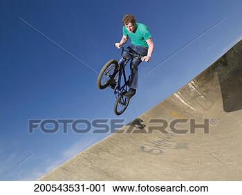 Stock Photography - young man performing 
stunt on bike 
against blue sky. 
fotosearch - search 
stock photos, 
pictures, images, 
and photo clipart