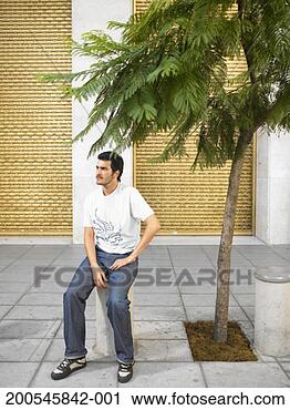 Stock Photography - young man sitting 
on bollard in 
street. fotosearch 
- search stock 
photos, pictures, 
images, and photo 
clipart