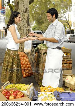 Stock Photography - young woman buying 
vegetables from 
market trader. 
fotosearch - search 
stock photos, 
pictures, images, 
and photo clipart