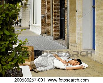 Stock Photography - young woman sleeping 
with pillow on 
pavement. fotosearch 
- search stock 
photos, pictures, 
images, and photo 
clipart