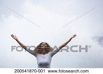 Stock Photography - young woman standing 
outdoors, arms 
raised, low angle 
view. fotosearch 
- search stock 
photos, pictures, 
images, and photo 
clipart