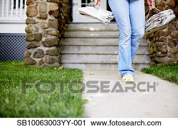 Stock Photography - mature woman outside 
house,  carrying 
newspapers tied 
up for. fotosearch 
- search stock 
photos, pictures, 
images, and photo 
clipart