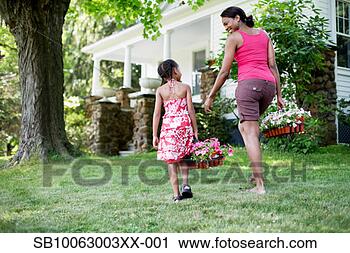 Stock Photography - mother and daughter 
(8-9 years) in 
garden outside 
house,  carrying. 
fotosearch - search 
stock photos, 
pictures, images, 
and photo clipart
