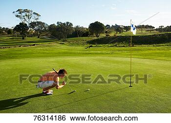 Stock Photo - teenage golfer 
(16-17) sighting 
putt on green, 
side view. fotosearch 
- search stock 
photos, pictures, 
images, and photo 
clipart