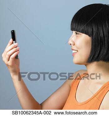 Stock Photo - young woman looking 
at text message 
on mobile phone, 
smiling, close-up. 
fotosearch - search 
stock photos, 
pictures, images, 
and photo clipart