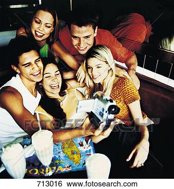 Stock Photo - group of friends 
using a digital 
video camera to 
record themselves. 
fotosearch - search 
stock photos, 
pictures, images, 
and photo clipart