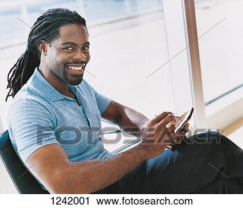 Stock Photography - portrait of a 
businessman sitting 
in a chair and 
using a handheld 
pc. fotosearch 
- search stock 
photos, pictures, 
images, and photo 
clipart