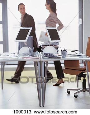 Stock Photo - two business colleagues 
walking behind 
desks in an office. 
fotosearch - search 
stock photos, 
pictures, images, 
and photo clipart