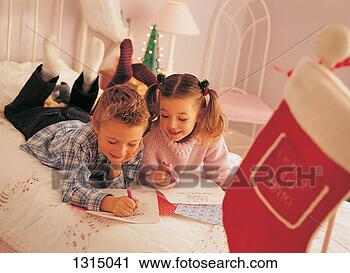 Stock Photography - brother and sister 
lying on a bed 
writing letters 
to father christmas. 
fotosearch - search 
stock photos, 
pictures, images, 
and photo clipart