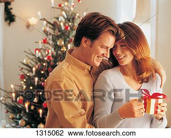 Stock Photo - man with his arm 
around a grateful 
woman holding 
a christmas present. 
fotosearch - search 
stock photos, 
pictures, images, 
and photo clipart