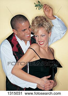 Stock Photography - smiling man standing 
with his arms 
around a woman 
holding mistletoe. 
fotosearch - search 
stock photos, 
pictures, images, 
and photo clipart