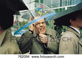Stock Photo - businessman standing 
in the rain with 
a toy umbrella. 
fotosearch - search 
stock photos, 
pictures, images, 
and photo clipart
