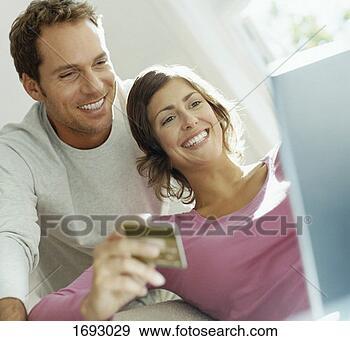 Stock Photograph - couple using bank 
card online with 
a laptop. fotosearch 
- search stock 
photos, pictures, 
images, and photo 
clipart