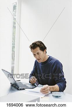 Stock Photo - man sits at a 
desk with his 
laptop,  paying 
a bill online 
with his. fotosearch 
- search stock 
photos, pictures, 
images, and photo 
clipart