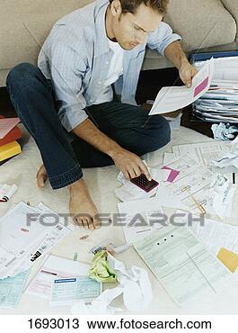 Stock Photo - man sits on floors 
surrounded by 
bills using a 
calculator. fotosearch 
- search stock 
photos, pictures, 
images, and photo 
clipart
