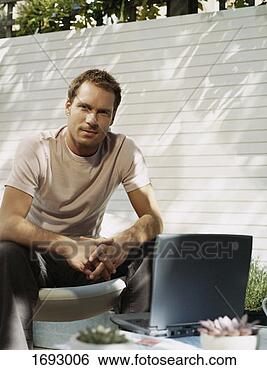 Stock Photo - man sitting in 
his garden in 
front of his laptop. 
fotosearch - search 
stock photos, 
pictures, images, 
and photo clipart