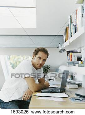 Stock Photo - serious looking 
man sits at his 
desk with a laptop 
in front of him. 
fotosearch - search 
stock photos, 
pictures, images, 
and photo clipart