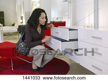 Stock Photo - woman examines 
a chest of drawers 
in an interiors 
shop. fotosearch 
- search stock 
photos, pictures, 
images, and photo 
clipart