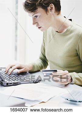 Picture - woman sits at 
a desk using a 
laptop and paying 
a bill online 
with her. fotosearch 
- search stock 
photos, pictures, 
images, and photo 
clipart