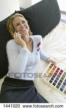 Stock Photography - woman sitting 
on a bed in a 
shop,  holding 
a colour swatch 
and using. fotosearch 
- search stock 
photos, pictures, 
images, and photo 
clipart