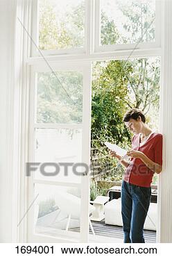 Stock Photography - woman stands by 
an open patio 
door examining 
a document. fotosearch 
- search stock 
photos, pictures, 
images, and photo 
clipart