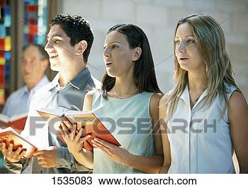 Stock Photo - four people standing 
in church, holding 
hymn books and 
singing. fotosearch 
- search stock 
photos, pictures, 
images, and photo 
clipart